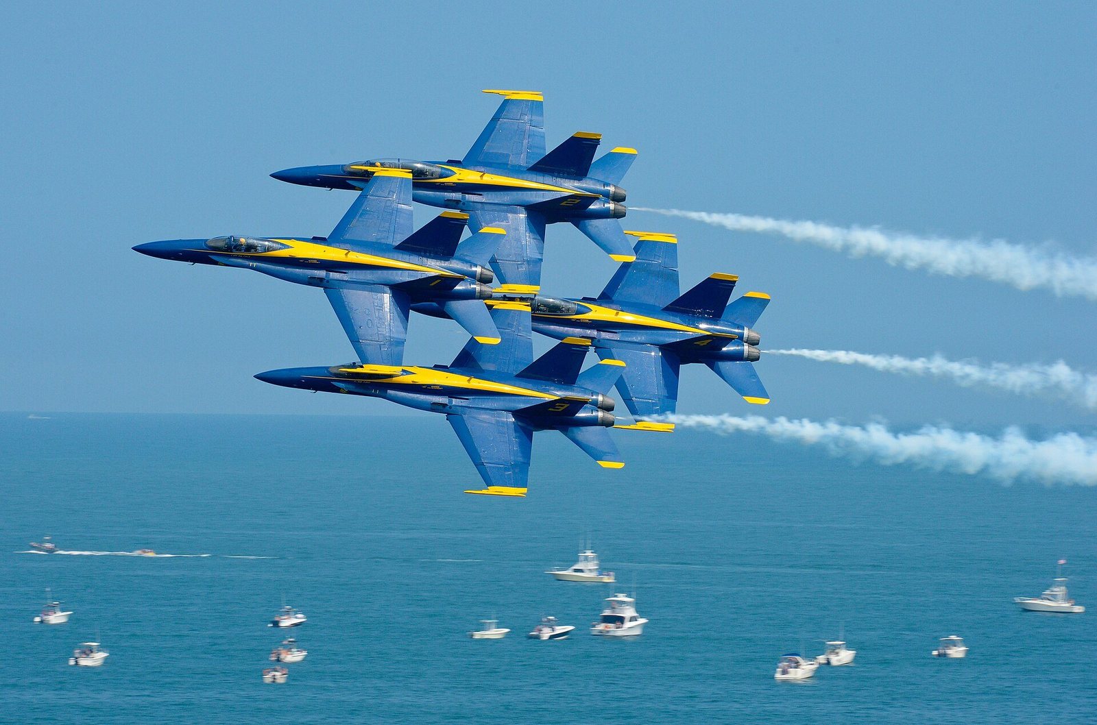 The Blue Angels flying in diamond formation over the ocean at the Ocean City Air Show, boats below